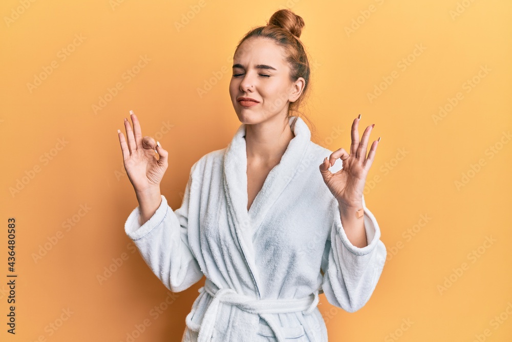 Young blonde woman wearing bathrobe relax and smiling with eyes closed doing meditation gesture with fingers. yoga concept. Young blonde woman wearing bathrobe relax and smiling with eyes closed doing meditation gesture with fingers. yoga concept.