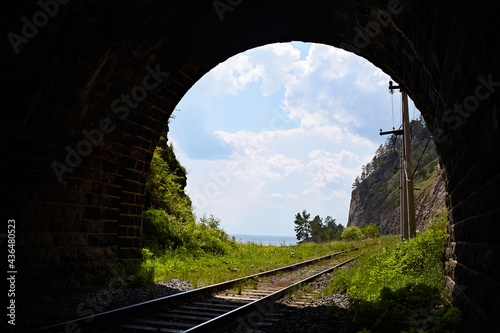 View from the old tunnel to Lake Baikal. Railway at the lake shore. Beautiful summer landscape, sky with clouds.