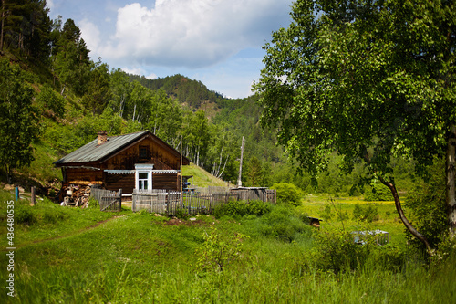 An old country house in the middle of a forest and mountains on a warm summer day. Seclusion, rural life. photo