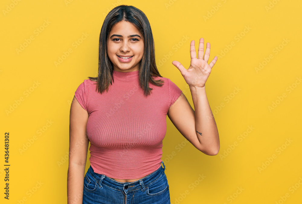Young hispanic girl wearing casual t shirt showing and pointing up with fingers number five while smiling confident and happy. Young hispanic girl wearing casual t shirt showing and pointing up with fingers number five while smiling confident and happy.