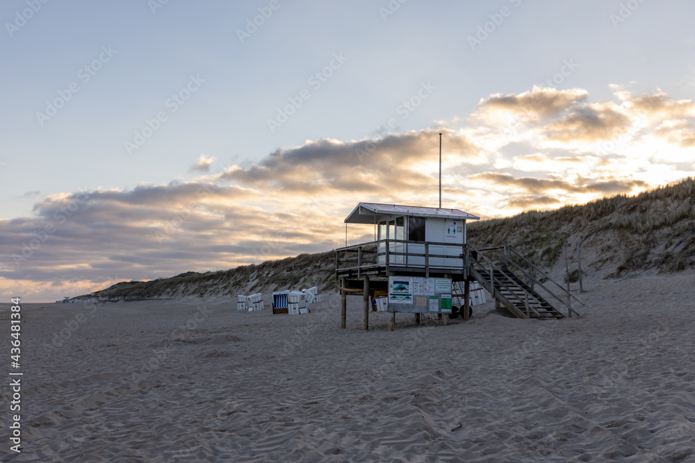 Beautiful beach on the German island of Sylt with white sand and a sunset sky. a lifeguard station and empty beach chairs. Beautiful beach on the German island of Sylt with white sand and a sunset sky. a lifeguard station and empty beach chairs.
