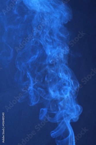 Shiny blue smoke of incense sticks making patterns.