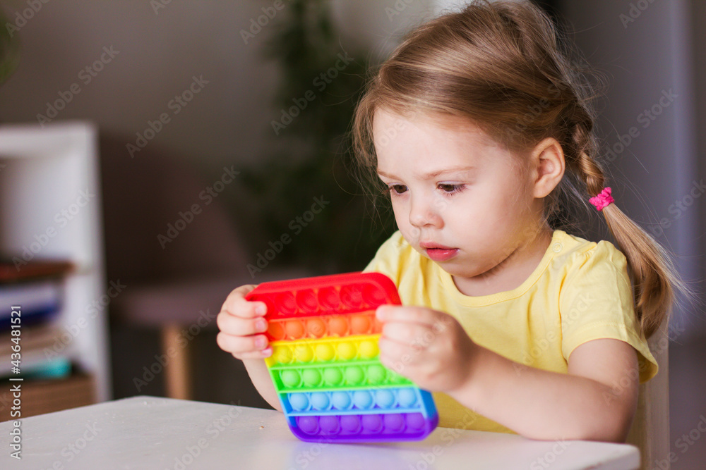 Little blonde girl children play with new trend sensory toy - rainbow pop it. Antistress toy for children and adult.Colorful toy simple dimple. Squishy soft bubble toys rainbow color Little blonde girl children play with new trend sensory toy - rainbow pop it. Antistress toy for children and adult.Colorful toy simple dimple. Squishy soft bubble toys rainbow color