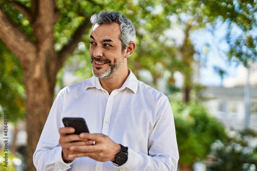 Middle age grey-haired man smiling happy using smartphone at the city. Middle age grey-haired man smiling happy using smartphone at the city.