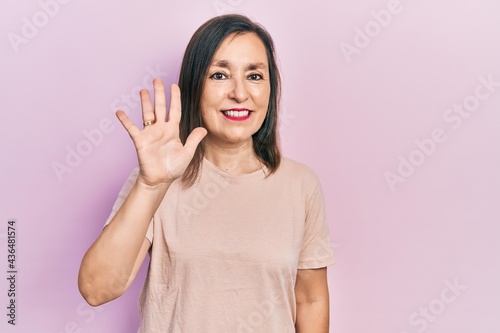 Middle age hispanic woman wearing casual clothes showing and pointing up with fingers number five while smiling confident and happy.
