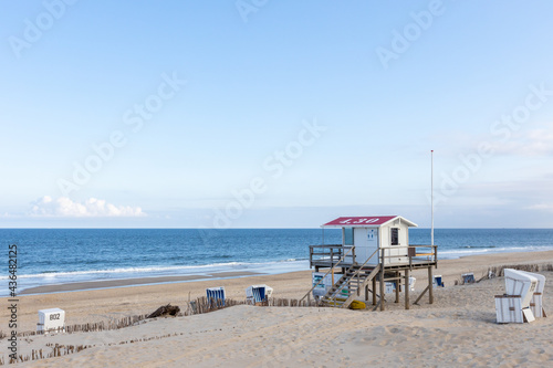 Beautiful beach on the German island of Sylt with white sand and a blue sky. a lifeguard station and empty  beach chairs. © 1take1shot