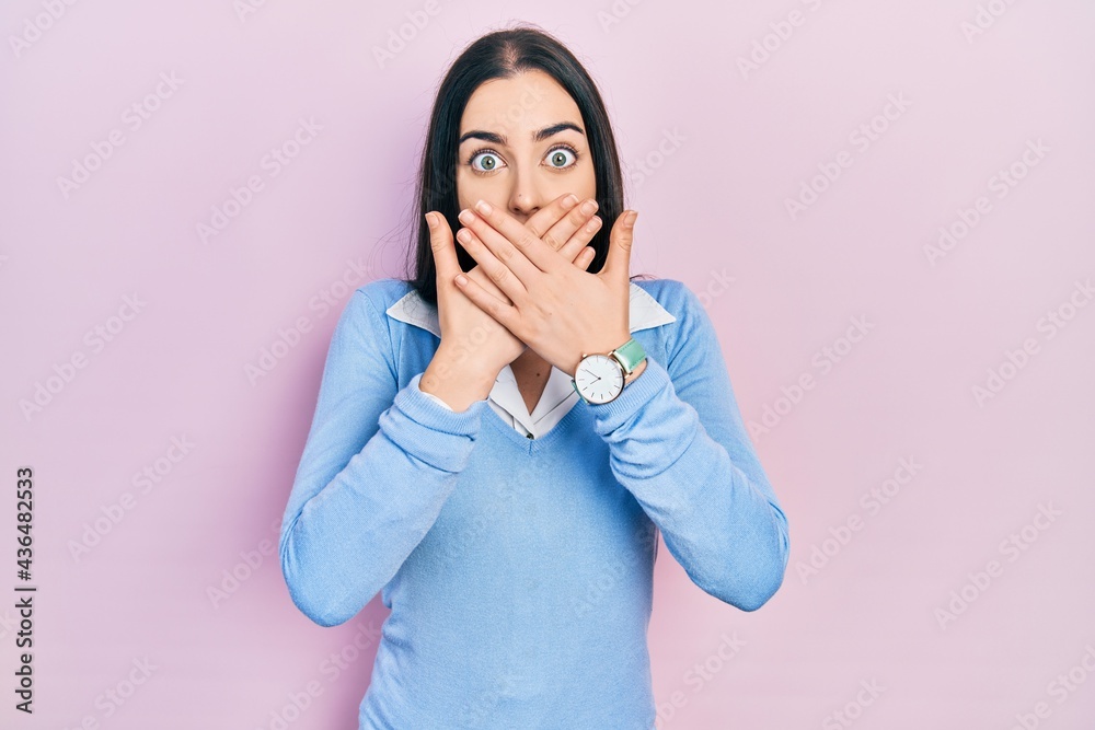Beautiful woman with blue eyes standing over pink background shocked covering mouth with hands for mistake. secret concept. Beautiful woman with blue eyes standing over pink background shocked covering mouth with hands for mistake. secret concept.