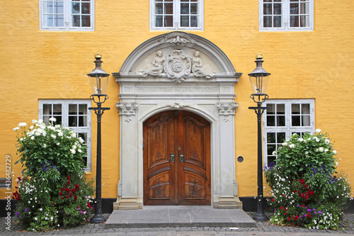 Entrance doorway of the Old City Hall. Beautiful historic yellow painted building with a wooden door in the city center, Aalborg, Denmark.