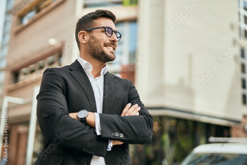 Young hispanic businessman with arms crossed smiling happy at the city.