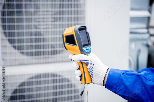 Technician uses a thermal imaging infrared thermometer to check the condensing unit heat exchanger.