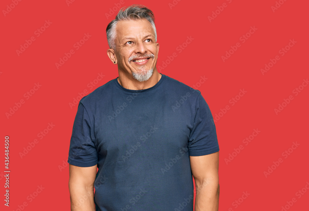 Middle age grey-haired man wearing casual clothes looking away to side with smile on face, natural expression. laughing confident. Middle age grey-haired man wearing casual clothes looking away to side with smile on face, natural expression. laughing confident.
