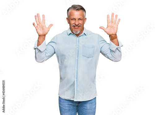 Middle age grey-haired man wearing casual clothes showing and pointing up with fingers number ten while smiling confident and happy.