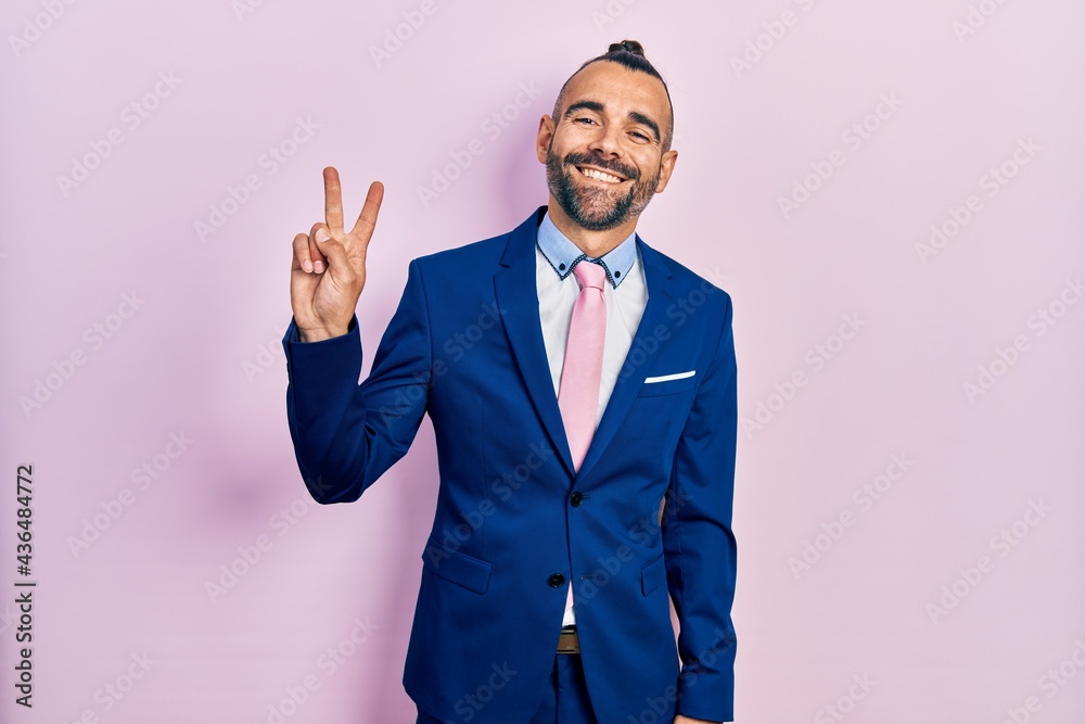 Young hispanic man wearing business suit and tie showing and pointing up with fingers number two while smiling confident and happy. Young hispanic man wearing business suit and tie showing and pointing up with fingers number two while smiling confident and happy.