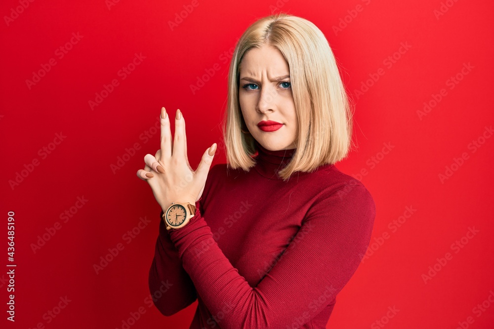 Young blonde woman wearing casual clothes holding symbolic gun with hand gesture, playing killing shooting weapons, angry face Young blonde woman wearing casual clothes holding symbolic gun with hand gesture, playing killing shooting weapons, angry face