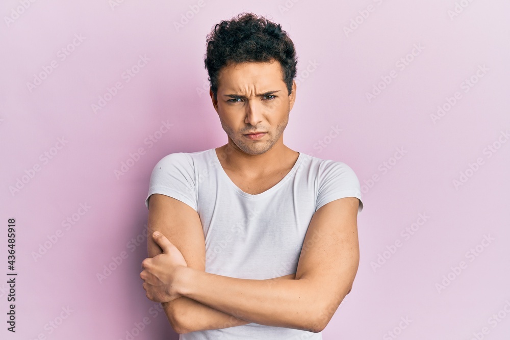 Obraz premium Young handsome man wearing casual white t shirt skeptic and nervous, disapproving expression on face with crossed arms. negative person.