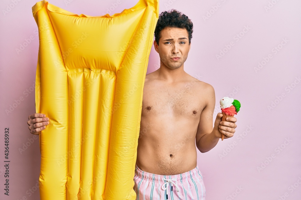 Obraz premium Young handsome man wearing swimsuit holding summer mattress float and icecream depressed and worry for distress, crying angry and afraid. sad expression.