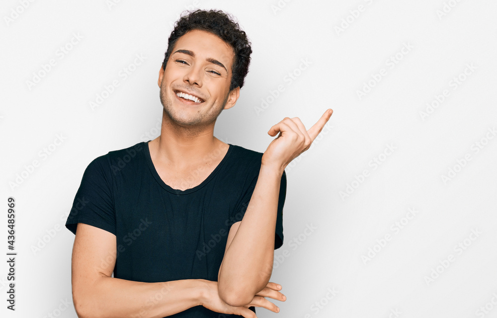 Young handsome man wearing casual black t shirt with a big smile on face, pointing with hand and finger to the side looking at the camera. Young handsome man wearing casual black t shirt with a big smile on face, pointing with hand and finger to the side looking at the camera.