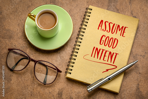 assume good intent inspirational handwriting in a spiral notebook with a cup coffee, positivity and personal development concept