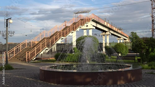 The fountain at the railway station, against the background of the pedestrian bridge over the railway