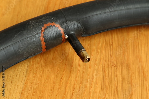 Repairing a bicyle tire. Patch over the hole. Copy space for text. Close up and isolated against a wooden floor. photo