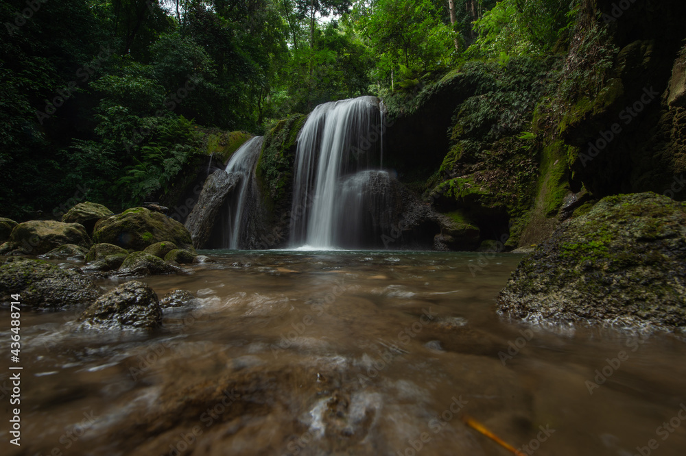 A two-tiered waterfall in a tropical rainforest features beautiful waterfalls of Nan Province in northern Thailand.