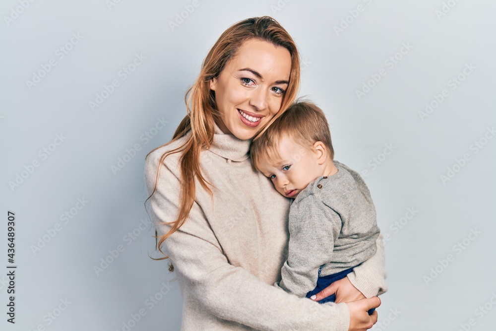 Young caucasian woman holding and hugging her son with love. Family of two bonding together. Mother holding infant toddler