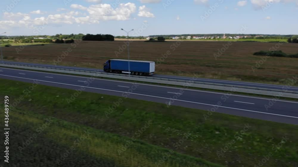 Aerial View Cargo Truck. Large Delivery Truck is Moving. Aerial Shot Of Lorry On Road In Beautiful Countryside. Aerial View of Semi-truck on Road In Summer Day Field of Wheat. Aerial View Cargo Truck. Large Delivery Truck is Moving. Aerial Shot Of Lorry On Road In Beautiful Countryside. Aerial View of Semi-truck on Road In Summer Day Field of Wheat.