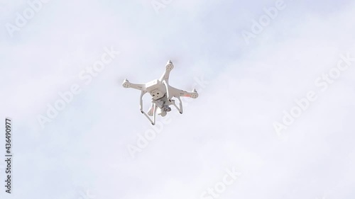 Single modern camera drone hovering, flying, seen from below, object closeup Filming drone up in the air detail shot up close, nobody, drone photography, filmmaking, drone laws concept, sky background