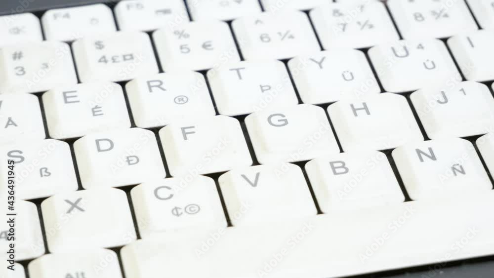 Man sanitizing, disinfecting, cleaning a white laptop keyboard extreme closeup, hand using a wet disinfectant wipe, damp tissue to disinfect, sanitize and clean a notebook, wiping an electronic device