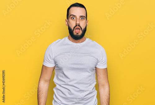 Young man with beard wearing casual white t shirt afraid and shocked with surprise and amazed expression, fear and excited face.