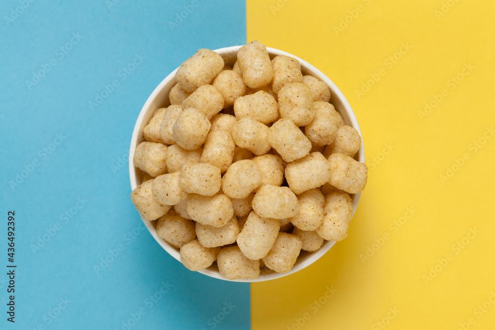 Close up of Cheese Potato Puff Snacks ball and buds, Popular Ready to eat crunchy and puffed snacks buds, cheesy salty pale-yellow color over blue yellow background - obrazy, fototapety, plakaty 