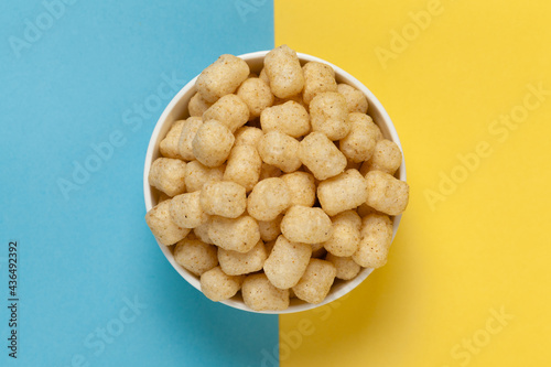 Close up of Cheese Potato Puff Snacks ball and buds, Popular Ready to eat crunchy and puffed snacks buds, cheesy salty pale-yellow color over blue yellow background