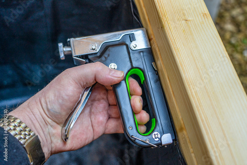 Close up of a carpenter using a brad nailer staple gun into wooden boards to repair  the inside covering of a. box