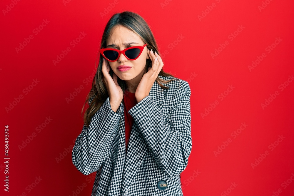 Young brunette woman wearing fashion and modern look covering ears with fingers with annoyed expression for the noise of loud music. deaf concept. Young brunette woman wearing fashion and modern look covering ears with fingers with annoyed expression for the noise of loud music. deaf concept.
