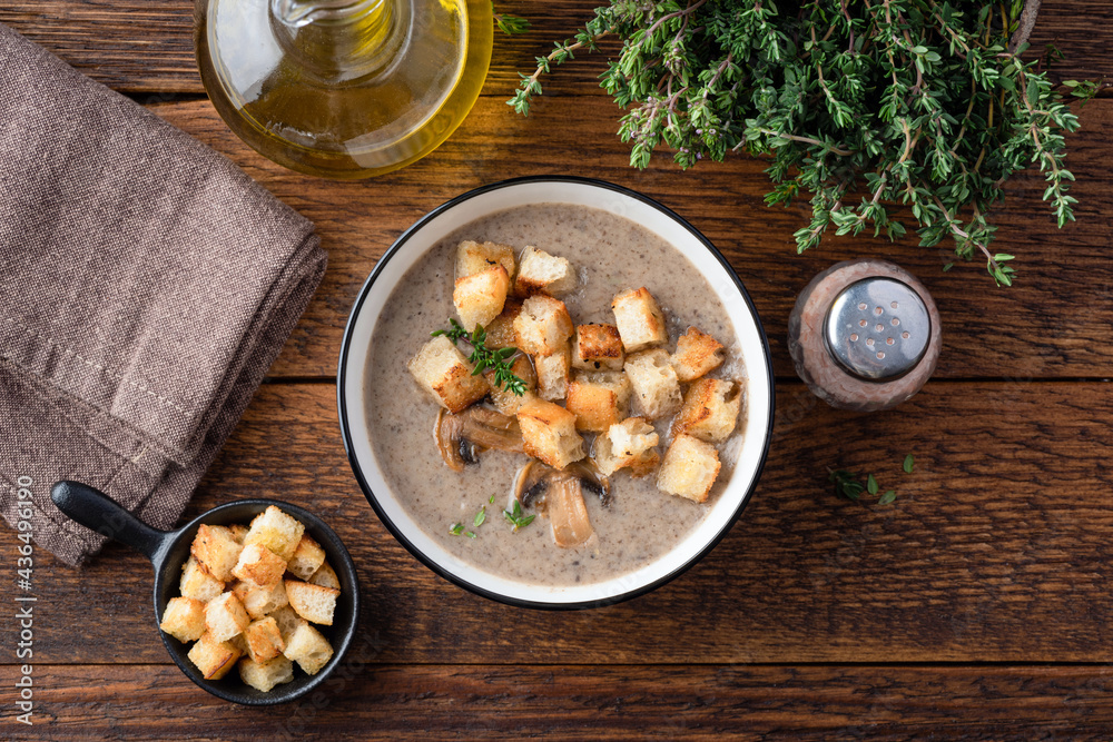 Cream of mushroom soup with croutons, thyme and olive oil on a wooden table background, top view Cream of mushroom soup with croutons, thyme and olive oil on a wooden table background, top view