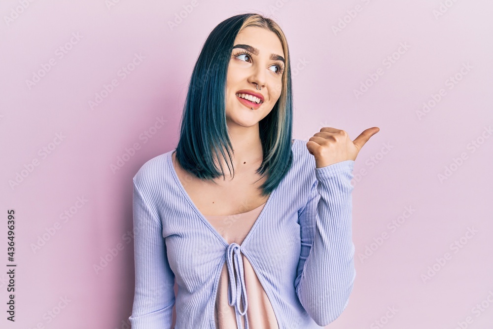 Young modern girl wearing casual jacket pointing thumb up to the side smiling happy with open mouth Young modern girl wearing casual jacket pointing thumb up to the side smiling happy with open mouth