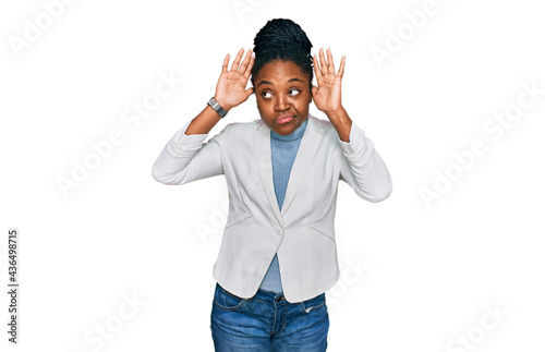 Young african american woman wearing business clothes doing bunny ears gesture with hands palms looking cynical and skeptical. easter rabbit concept. photo