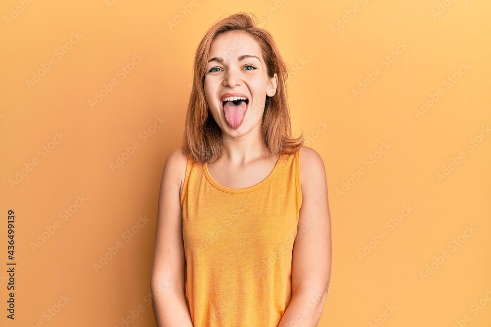 Young caucasian woman wearing casual style with sleeveless shirt sticking tongue out happy with funny expression. emotion concept. Young caucasian woman wearing casual style with sleeveless shirt sticking tongue out happy with funny expression. emotion concept.