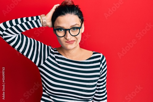 Young caucasian woman wearing casual clothes and glasses confuse and wonder about question. uncertain with doubt, thinking with hand on head. pensive concept.