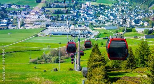 A cabin cable car travels up a mountain in summer photo
