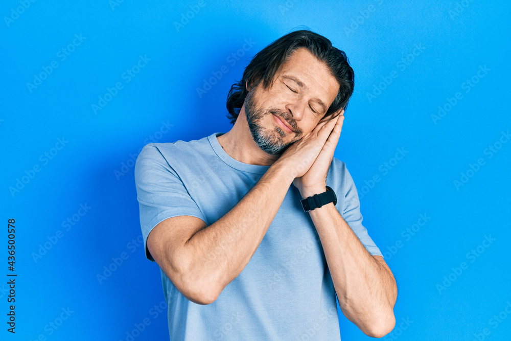 Middle age caucasian man wearing casual clothes sleeping tired dreaming and posing with hands together while smiling with closed eyes. Middle age caucasian man wearing casual clothes sleeping tired dreaming and posing with hands together while smiling with closed eyes.