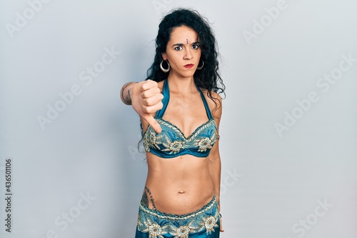 Young woman wearing bindi and traditional belly dance clothes looking unhappy and angry showing rejection and negative with thumbs down gesture. bad expression.