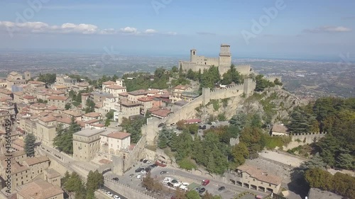 drone flying panoramic left around the city and san marino towers at the top of the mountain  in Italy