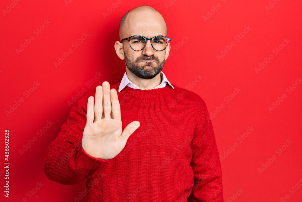 Young bald man wearing casual clothes and glasses doing stop sing with palm of the hand. warning expression with negative and serious gesture on the face. Young bald man wearing casual clothes and glasses doing stop sing with palm of the hand. warning expression with negative and serious gesture on the face.