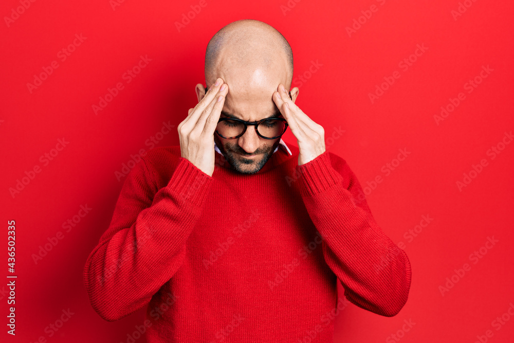 Young bald man wearing casual clothes and glasses with hand on head for pain in head because stress. suffering migraine.