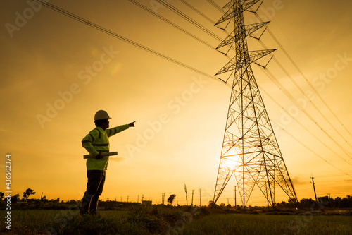 Engineer silhouette standing at power station planning work on power generation at high voltage electrodes.