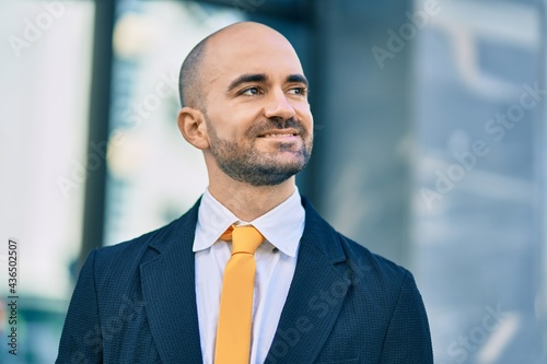 Young hispanic bald businessman smiling happy standing at the city.
