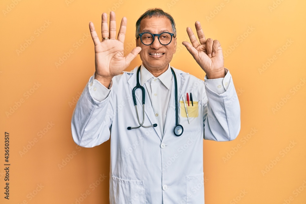 Middle age indian man wearing doctor coat and stethoscope showing and pointing up with fingers number eight while smiling confident and happy. Middle age indian man wearing doctor coat and stethoscope showing and pointing up with fingers number eight while smiling confident and happy.
