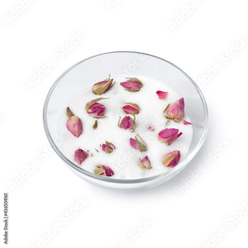 Dried rose buds in a glass cup with white sugar to obtain the rose taste and odor isolated on white background 