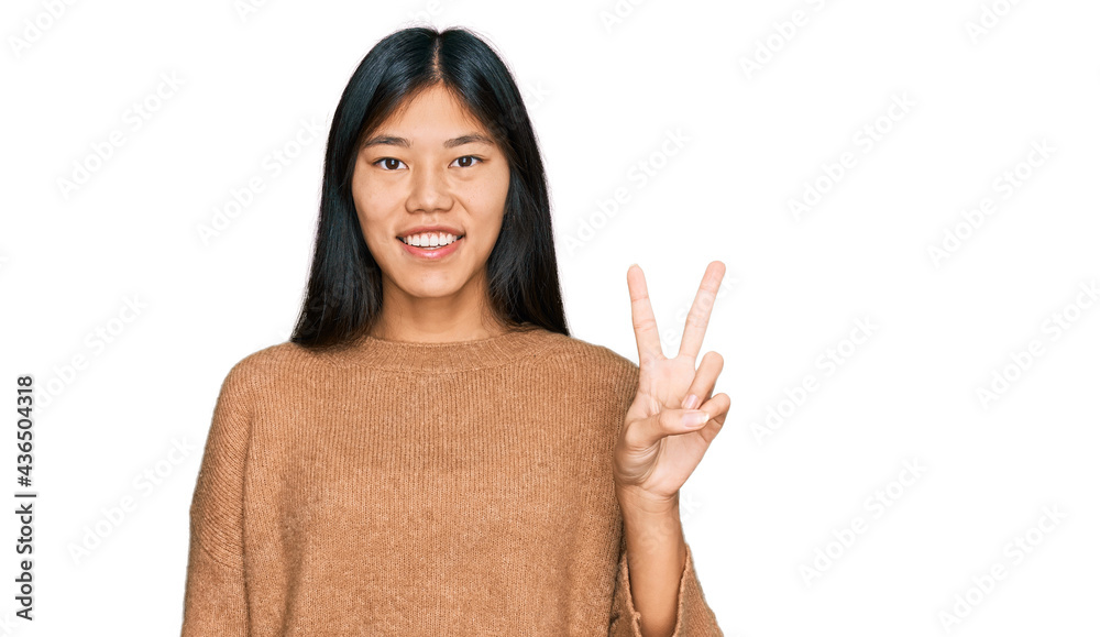Beautiful young asian woman wearing casual winter sweater showing and pointing up with fingers number two while smiling confident and happy. Beautiful young asian woman wearing casual winter sweater showing and pointing up with fingers number two while smiling confident and happy.